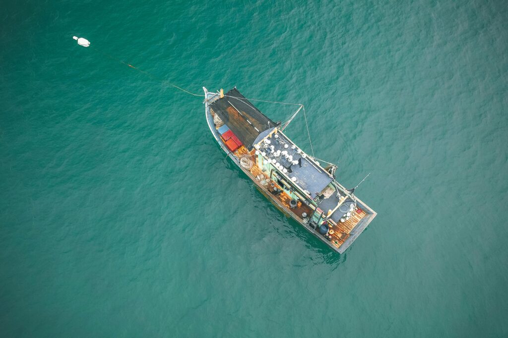 Drone view of big fishing vessel moored on rippling azure seawater on clear summer day